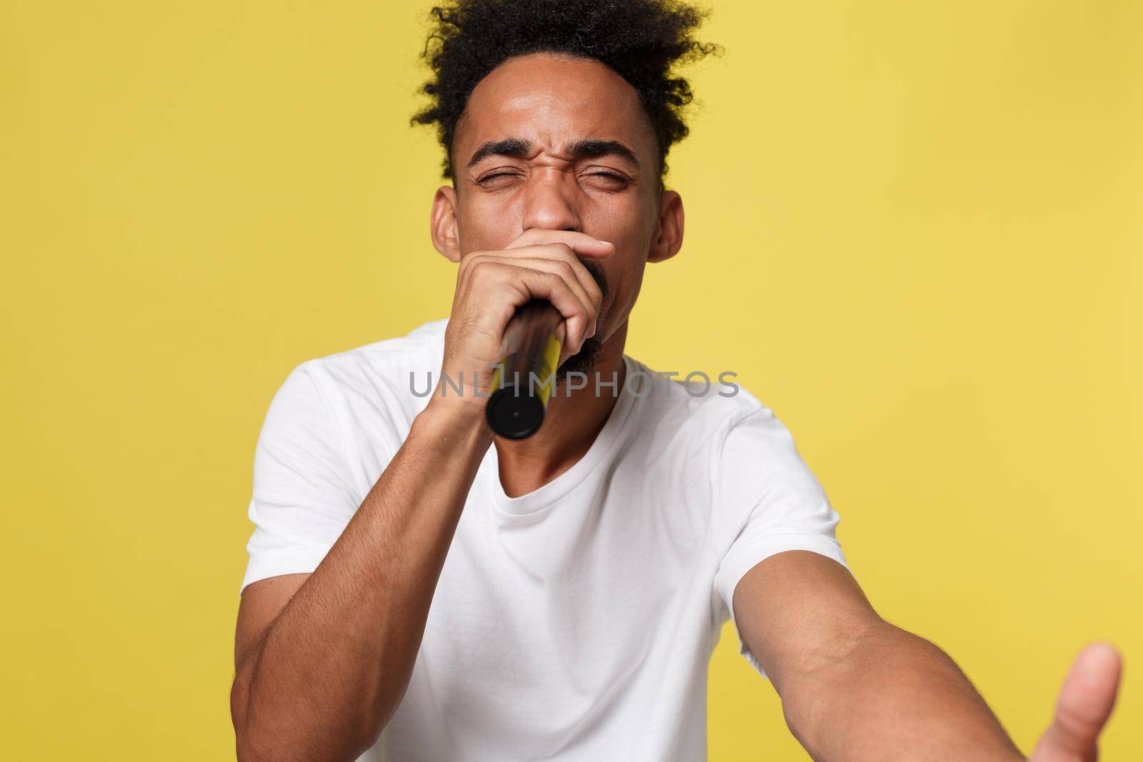 Stylish afro american man singing into microphone isolated on a yellow gold background by Benzoix