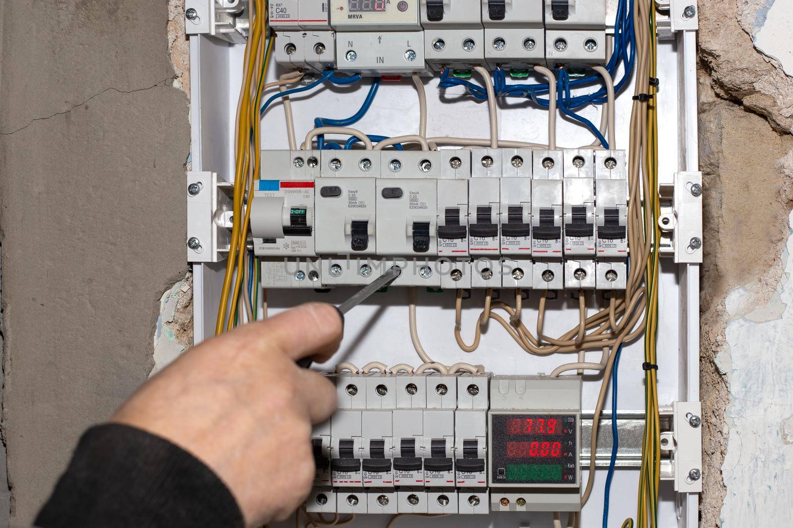 Electrical switchboard. A electrician installs a multifunctional shield to control electricity into the wall of the house.