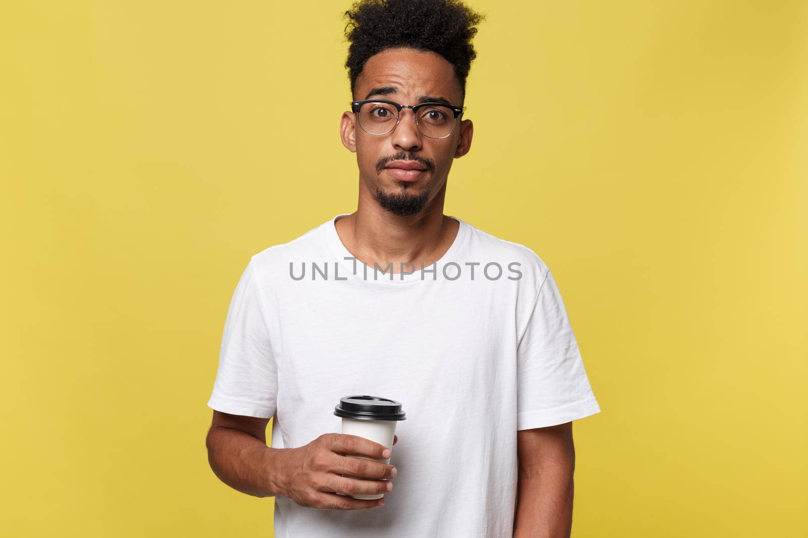 Stylish young afro american man holding cup of take away coffee isolated over yellow background.