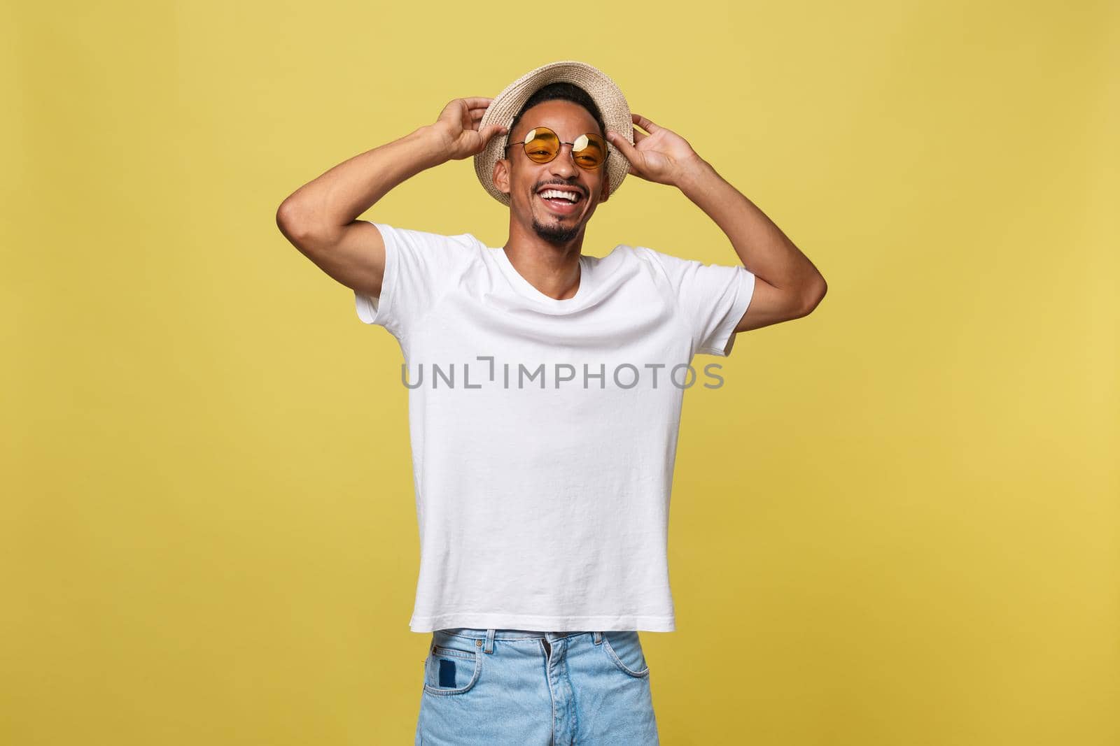 Close up portrait of young afro american shocked tourist , holding his eyewear, wearing tourist outfit, hat, with wide open eyes