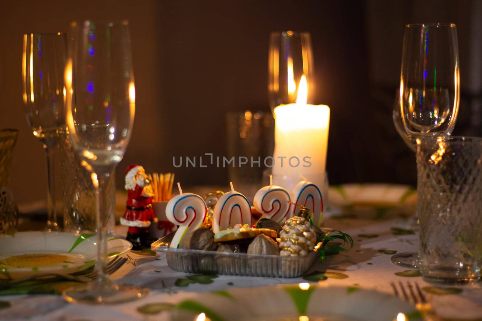 Christmas table with utensils and glasses, a table with burning candles, in a dark room
