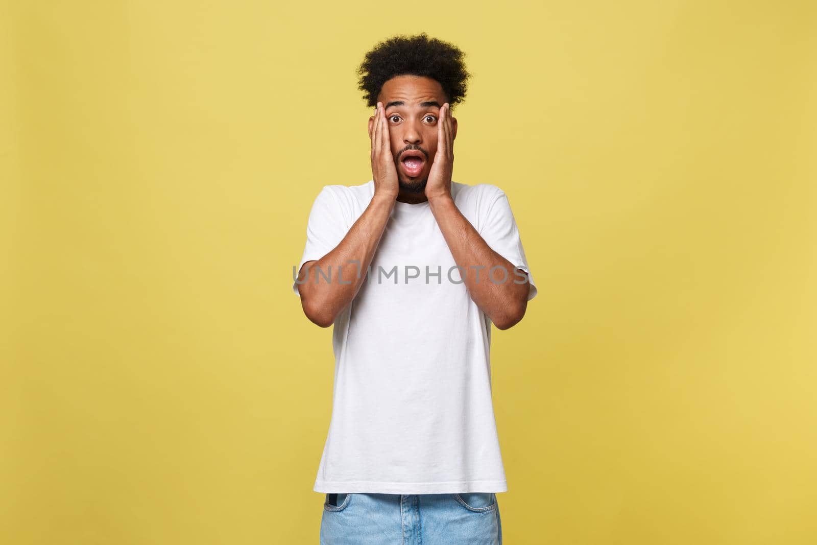 Emotional and People Concept - Portrait of excited young African American man screaming in shock and amazement holding hands on head. by Benzoix