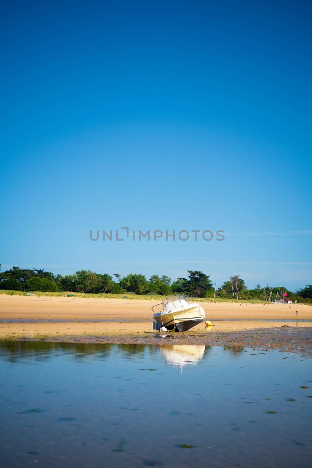 A motorboat laying on the beach at lowtide on a sunny summertime on the Isle of île de re in the Charente-Maritime in France