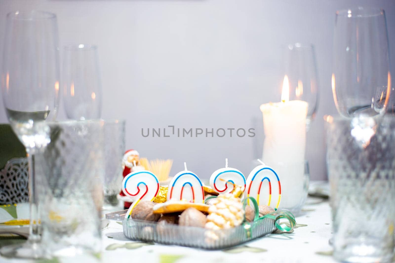 Christmas table with utensils and glasses, a table with burning candles, in a dark room