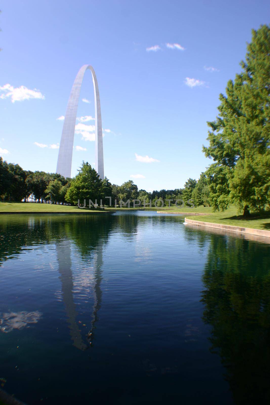 Image of Landscape shot of the St Louis Arch reflected in a lake neaer a group of trees