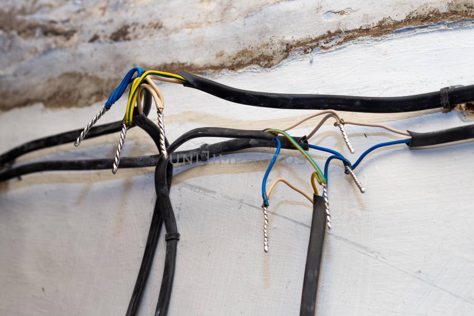 Connection of wires against the background of a wall in a house under construction. Twisting, soldering, welding of electrical cables by levnat09