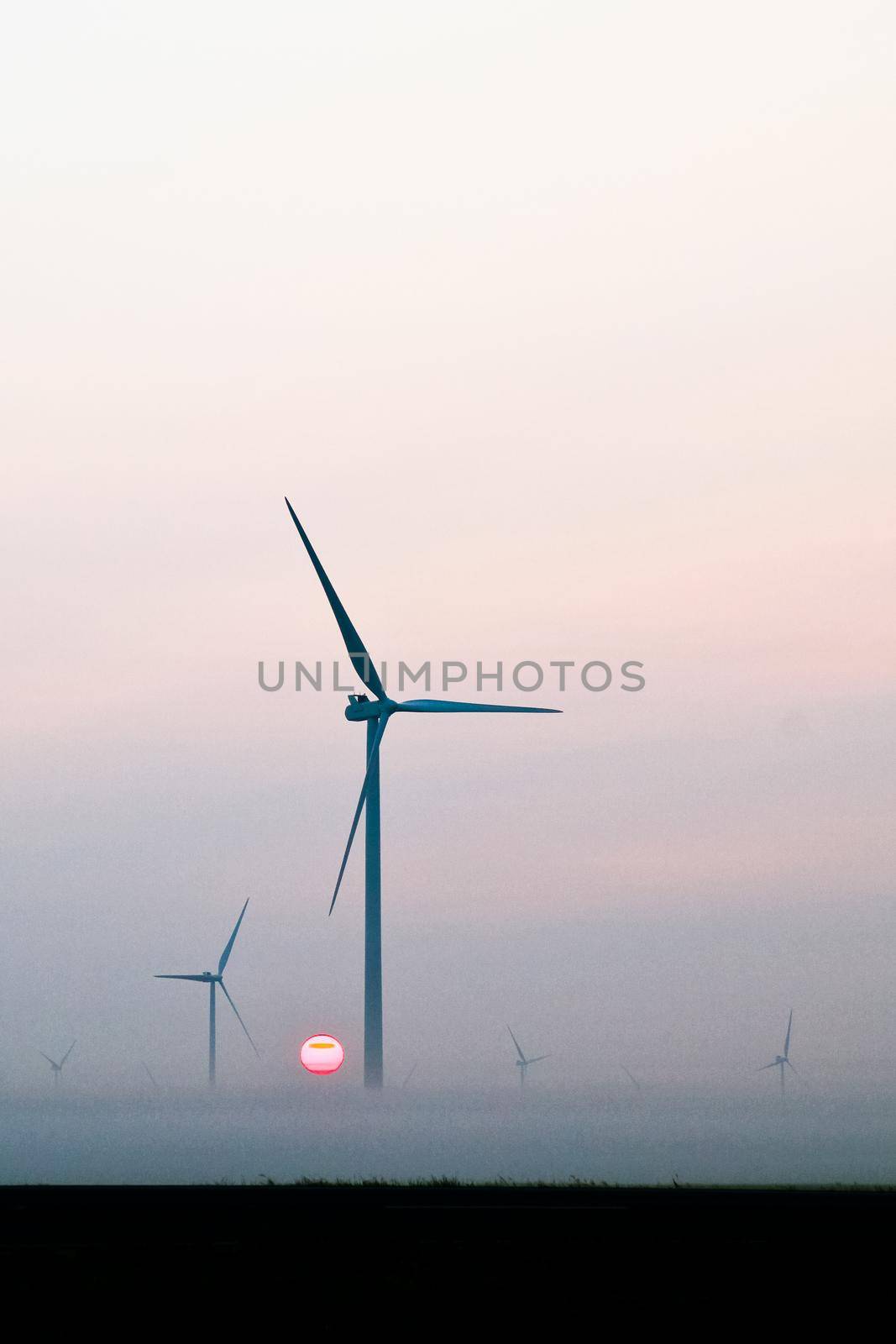 Image of Two windmills silhouetted against the morning sun