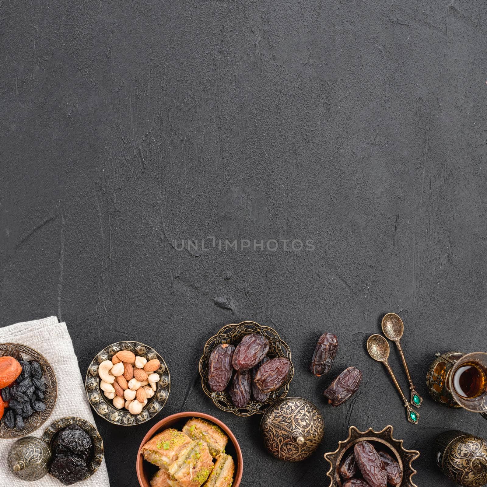 overhead view dates nuts baklava metallic plates black concrete textured backdrop with copy space. High quality photo by Zahard