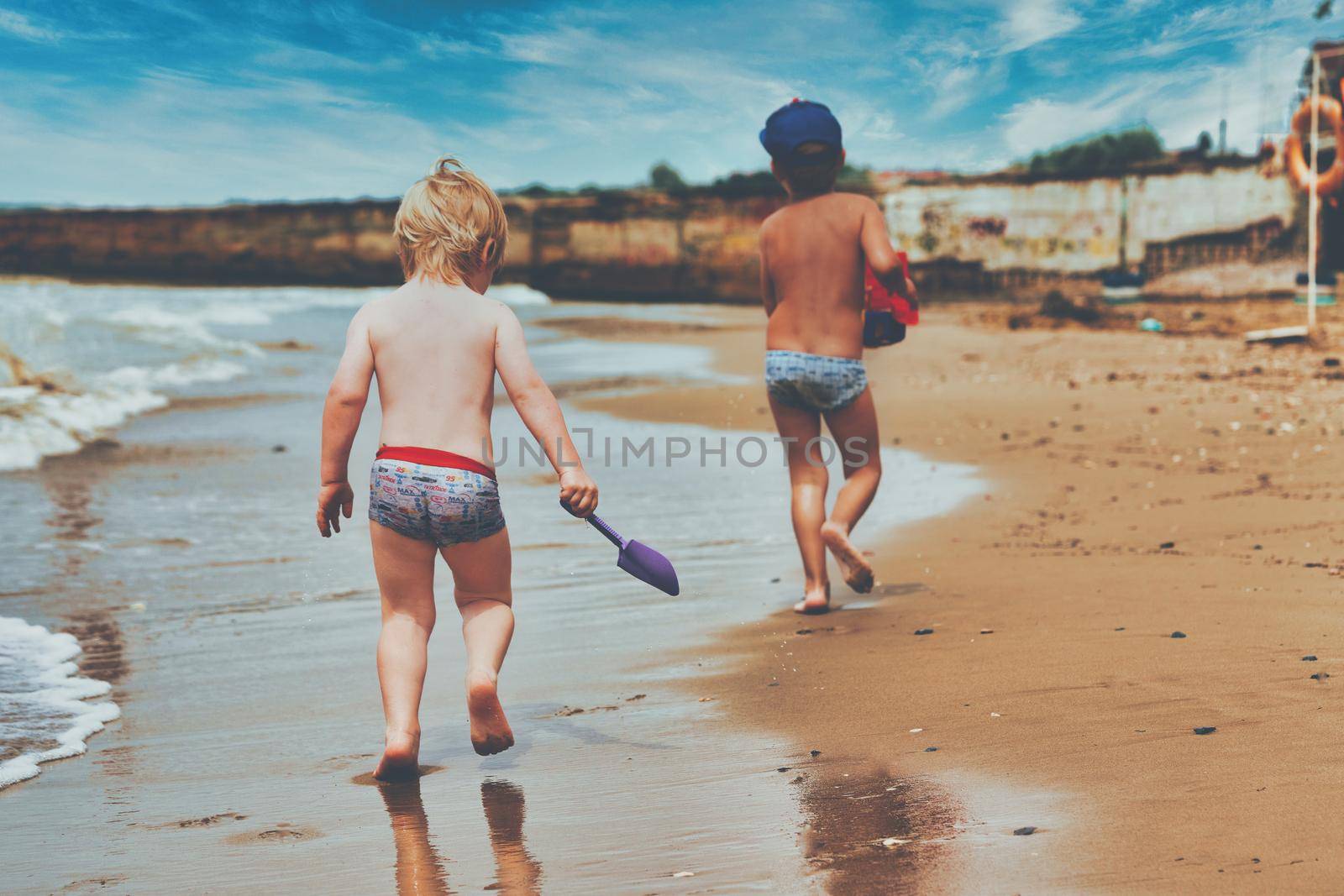 Two little boys are playing on the seashore. Children playing on the beach