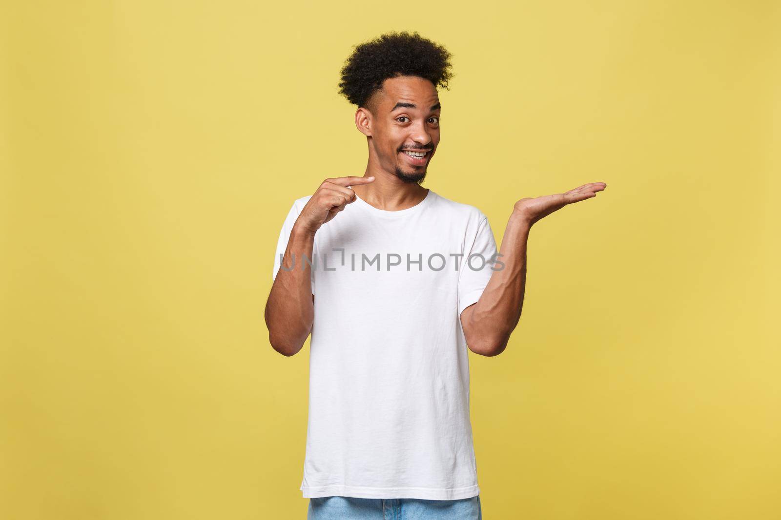 Charming handsome young black man holding his hand up to show present sell product. Isolated over yellow background