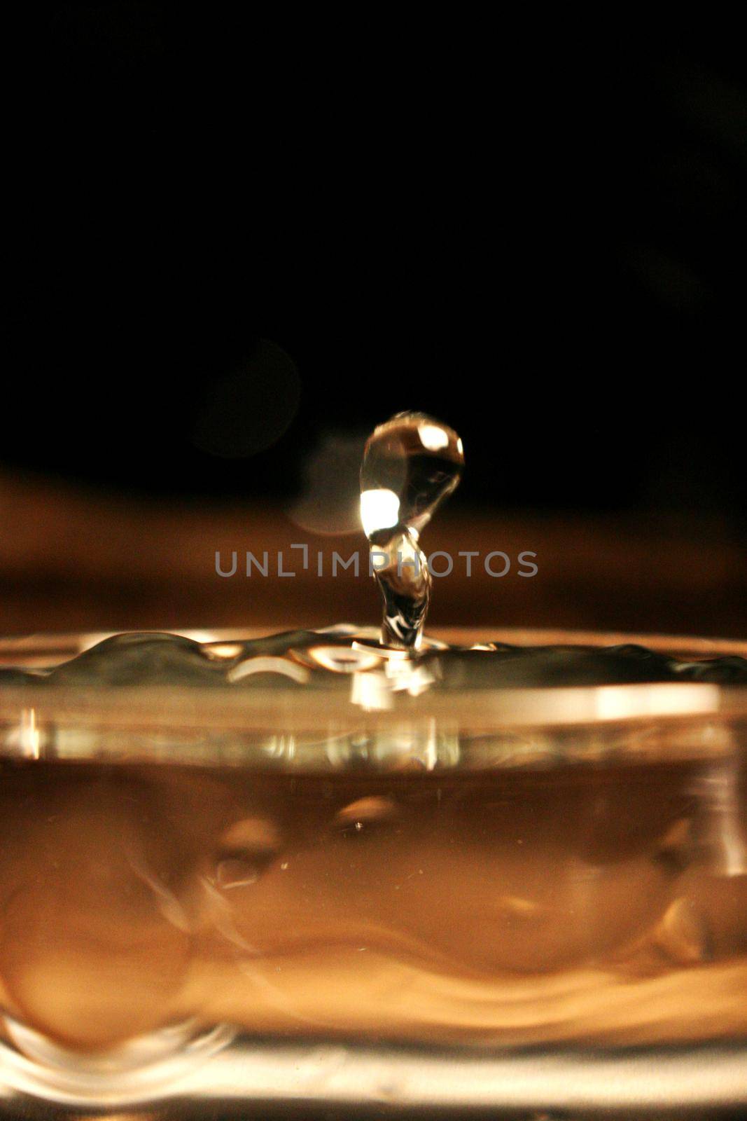 Image of Water splashes in a glass on a brown amber background