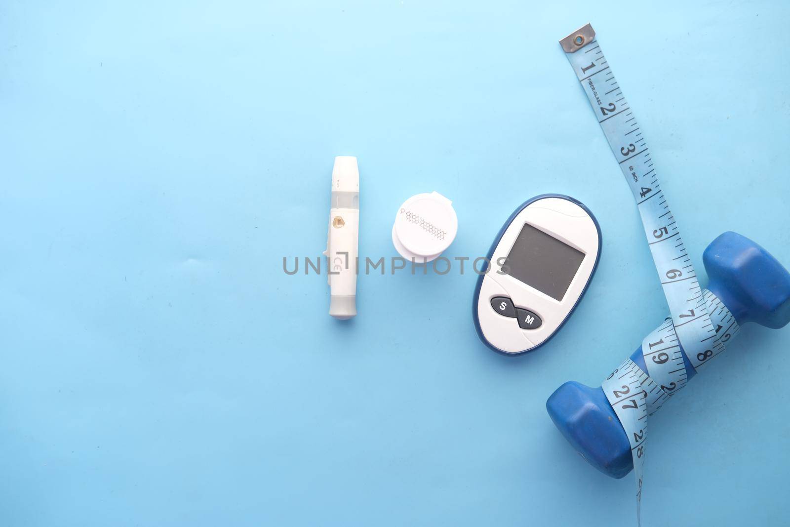 diabetic measurement tools and a dumbbell on blue background.