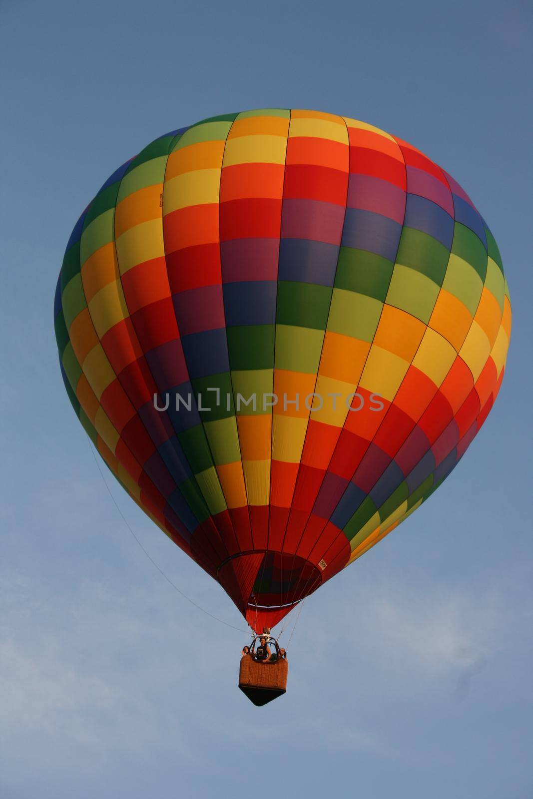 A hot air balloon with rainbow squares pattern flying in a cloudy sky by njproductions