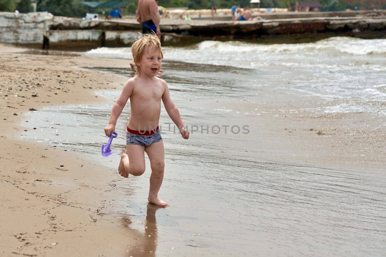 A little boy runs along the sandy beach along the seashore. Child resting on the sea