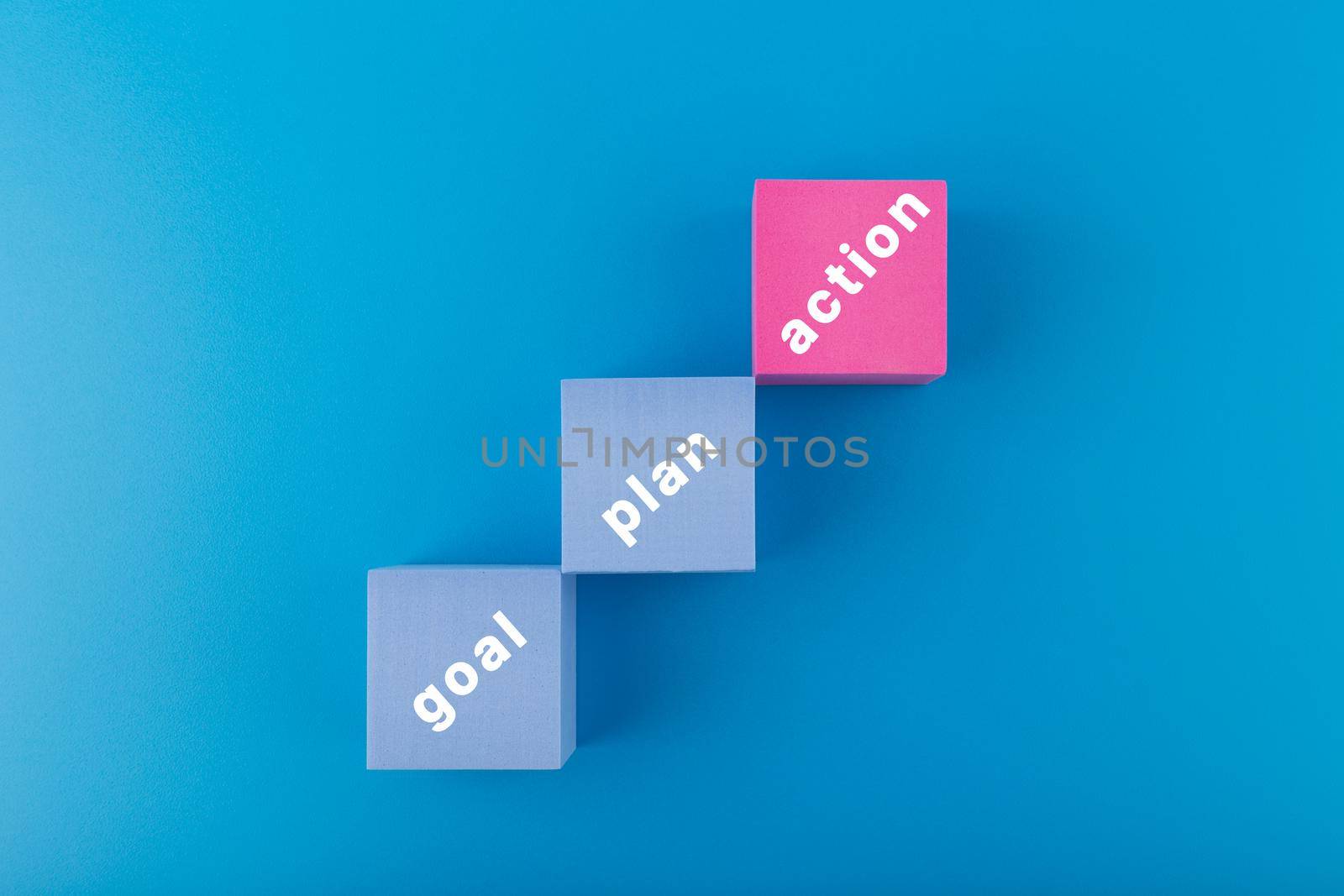 Business development, reaching a goal and success concept. Laddder with goal, plan, action written on toy blocks on dark blue background. High quality photo