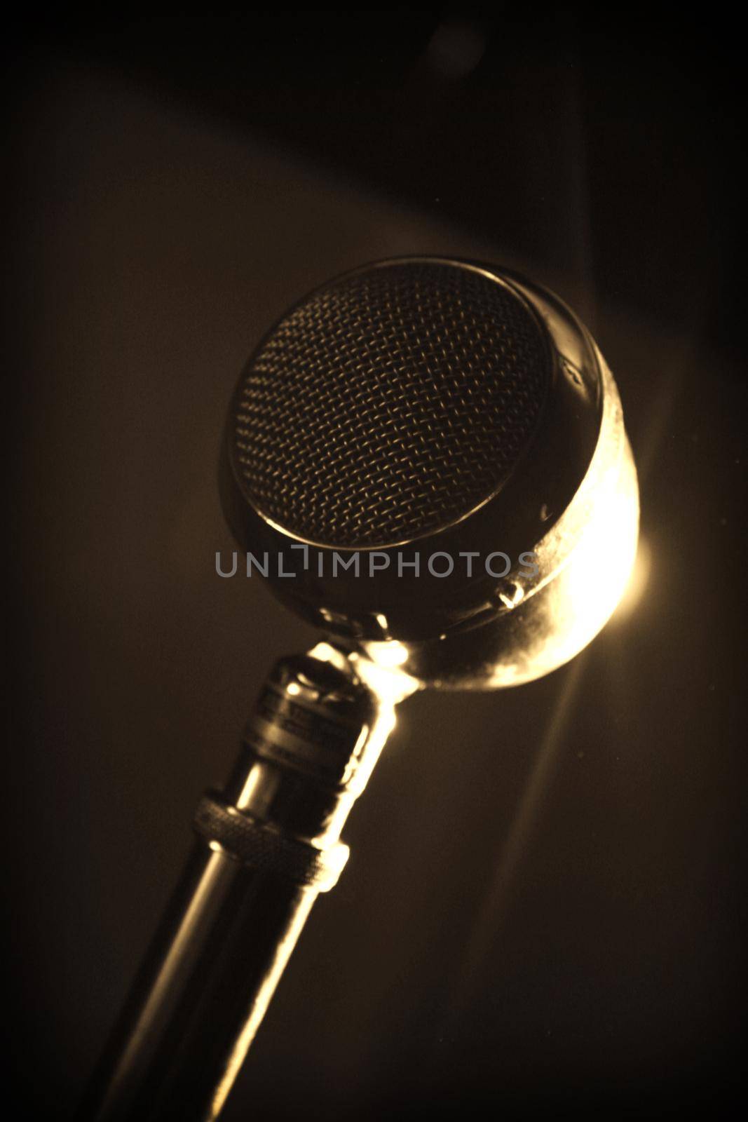 Image of Old metal circular microphone with a gold lens flare