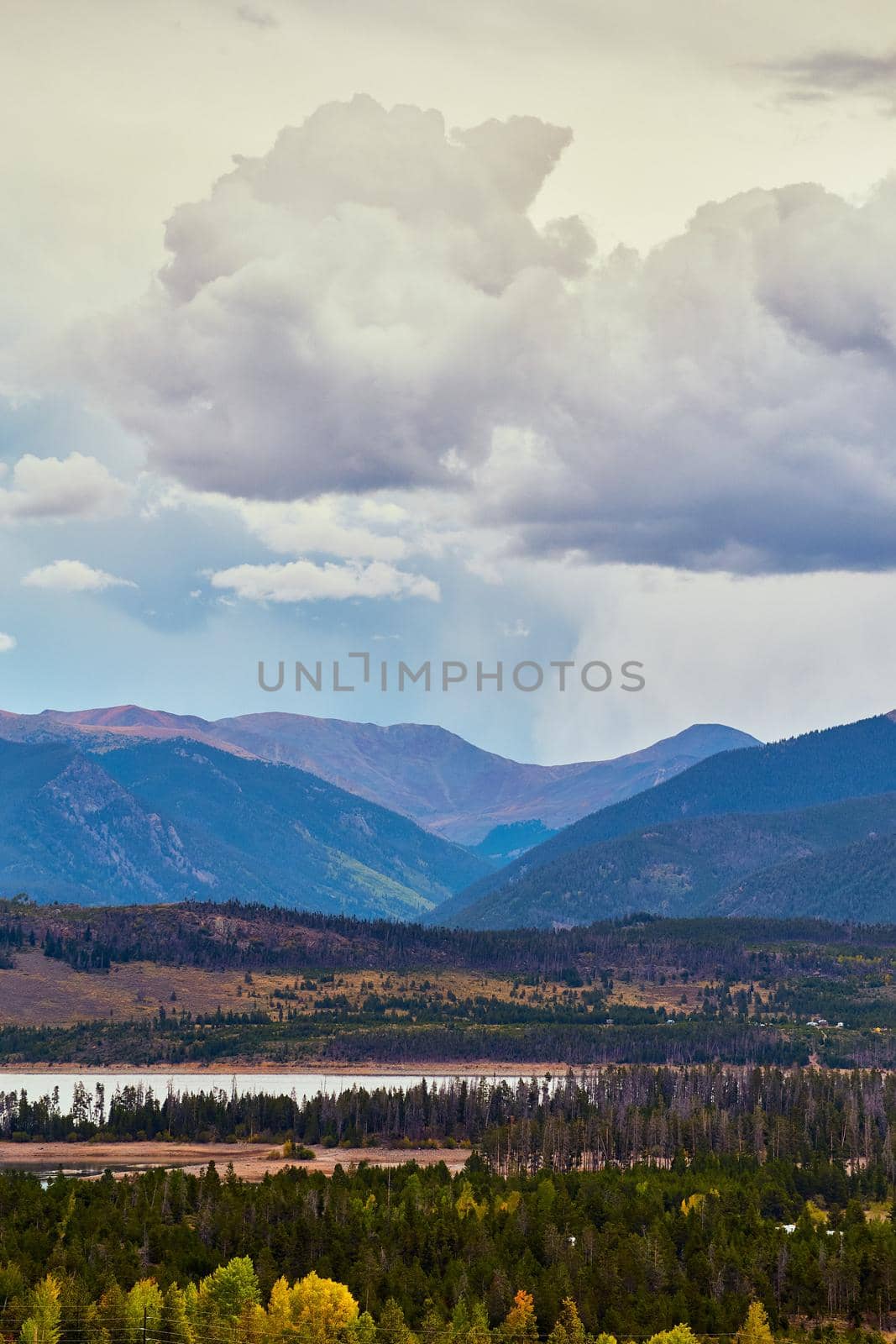 Vertical of mountains with rain clouds and water with pine trees surrounding by njproductions