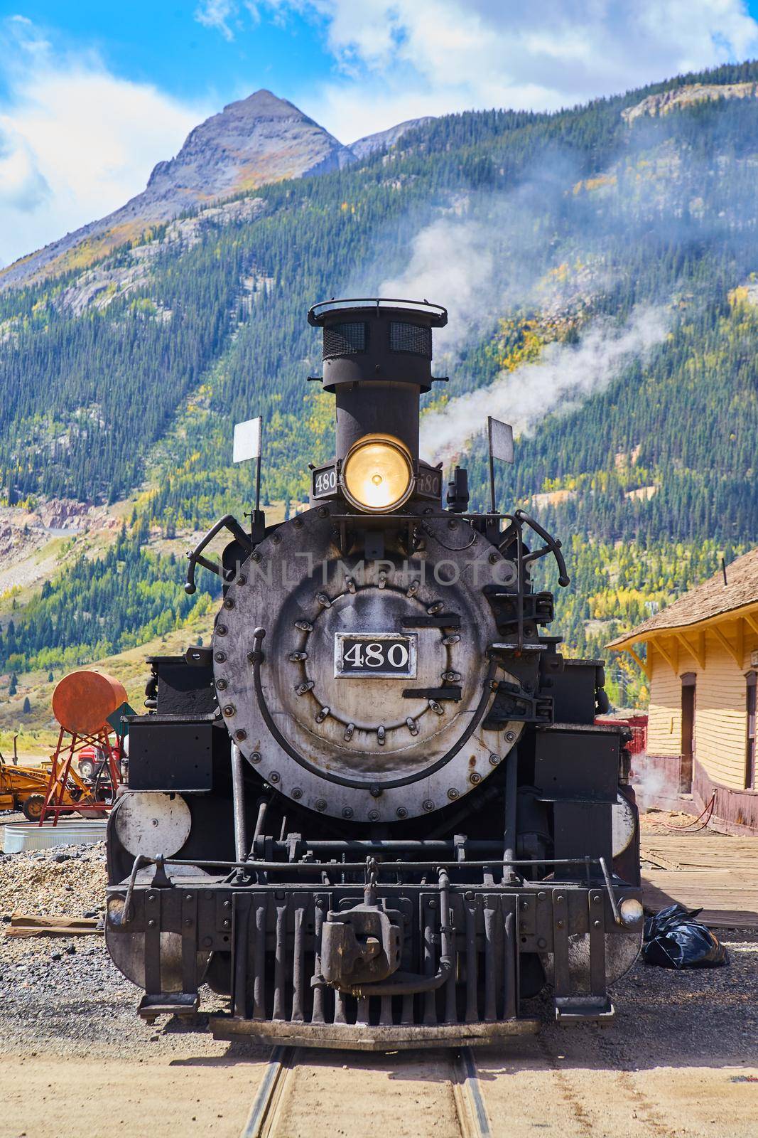 Image of Vertical close-up front of locomotive train with wall of mountains in the background