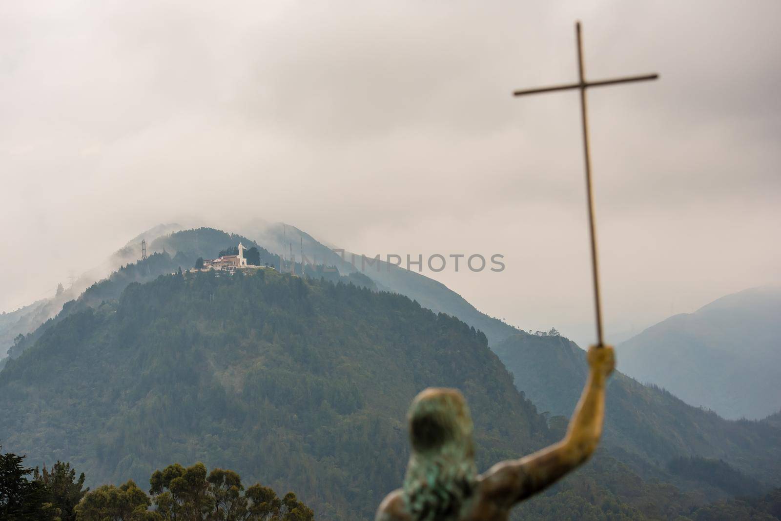 Statue of Jesus on Mount Monserrate holding a cross with mountain and clouds in the background. El Senor Caido