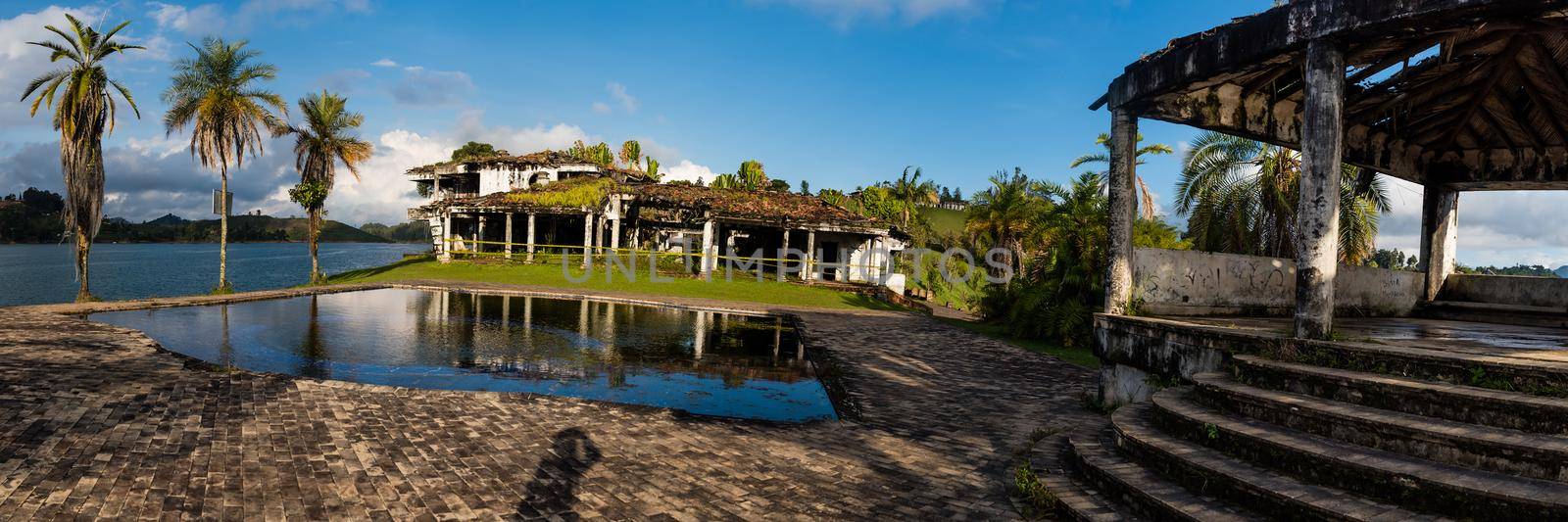 Guatape, Colombia - December 12, 2017: Pablo Escobar's old estate La Manuela in ruin with palm trees pool and river in view. Panoramic view
