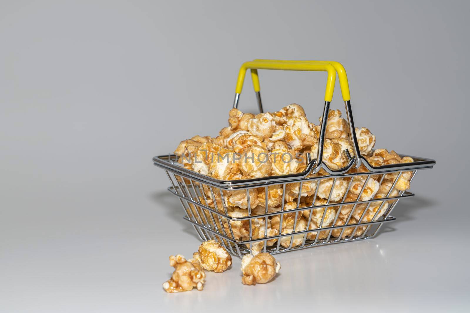 steel supermarket basket with popcorn on a gray background close-up by roman112007