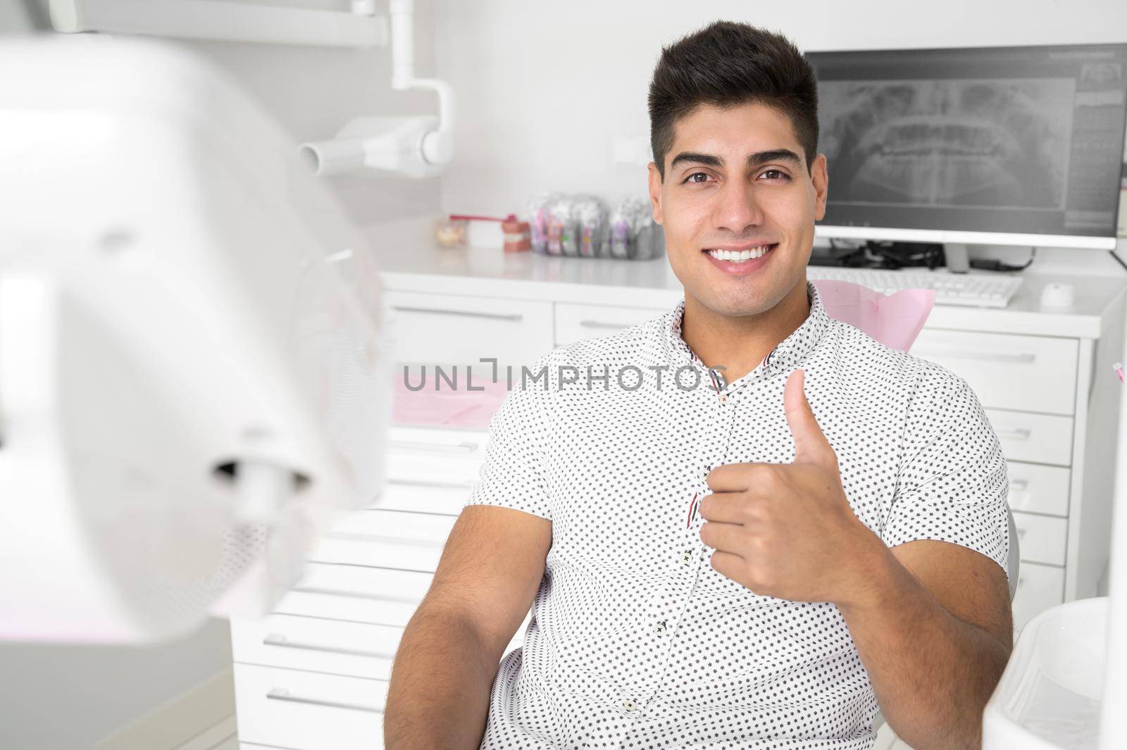 Man giving thumbs up at dentist office by HERRAEZ