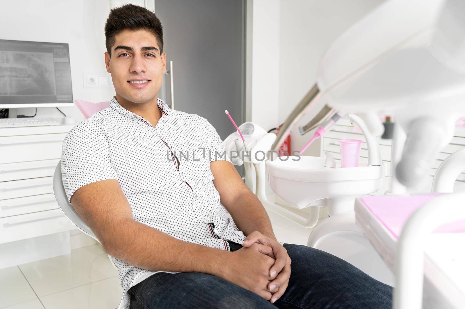 Portrait of a positive handsome patient smiling looking at camera, after treatment at dental clinic. High quality photo.