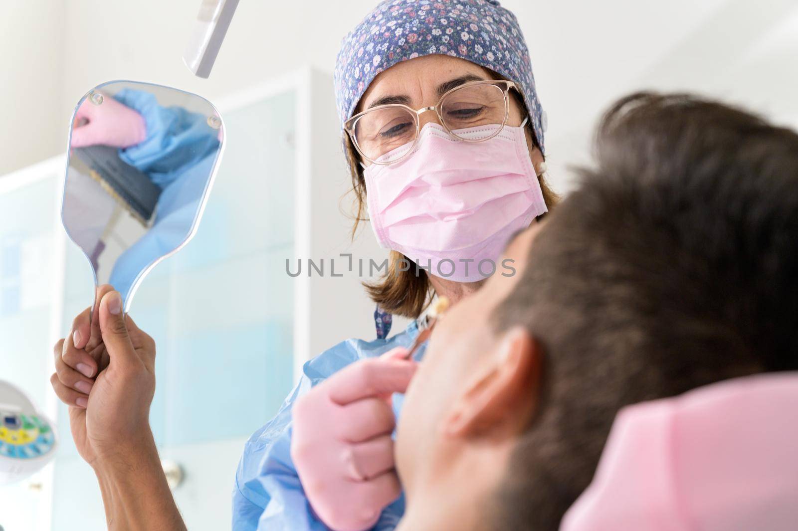 Patient looking teeth in mirror at dental clinic. High quality photo.