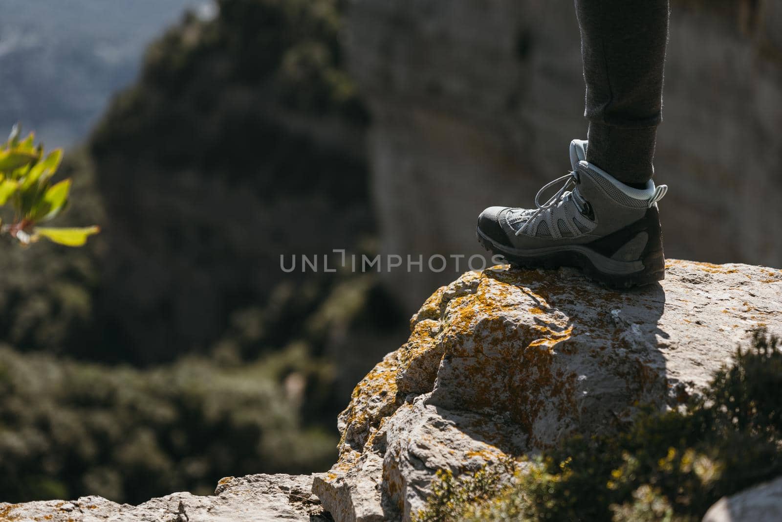 Hiking shoe stepping on a small rock with blurred landscape background on sunny day. Copy space