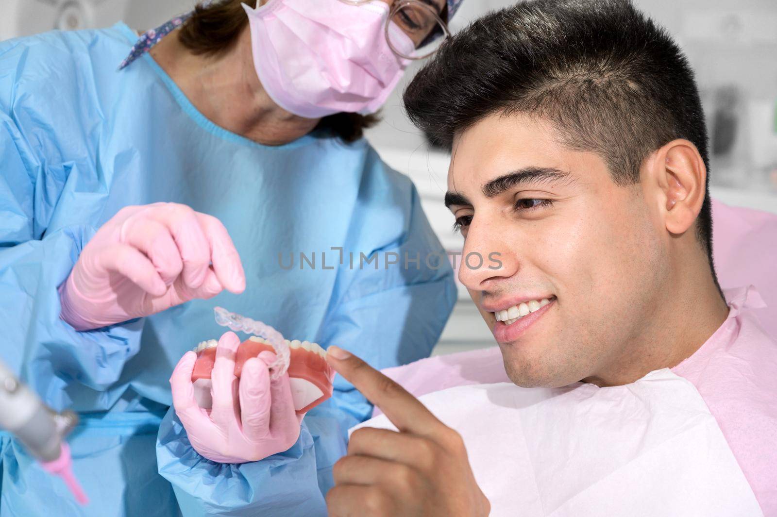 Dentist shows invisible braces aligner. Dental consultation in an orthodontic clinic by HERRAEZ