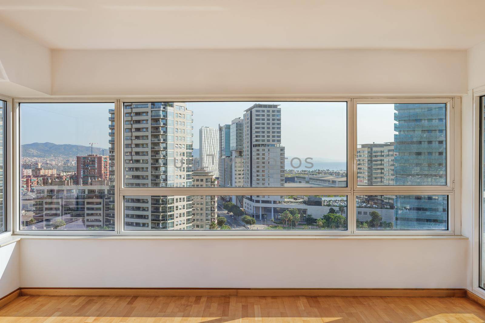 Sunny living room with big windows in the morning with panoramic view to the district with modern buildings in Barcelona by apavlin