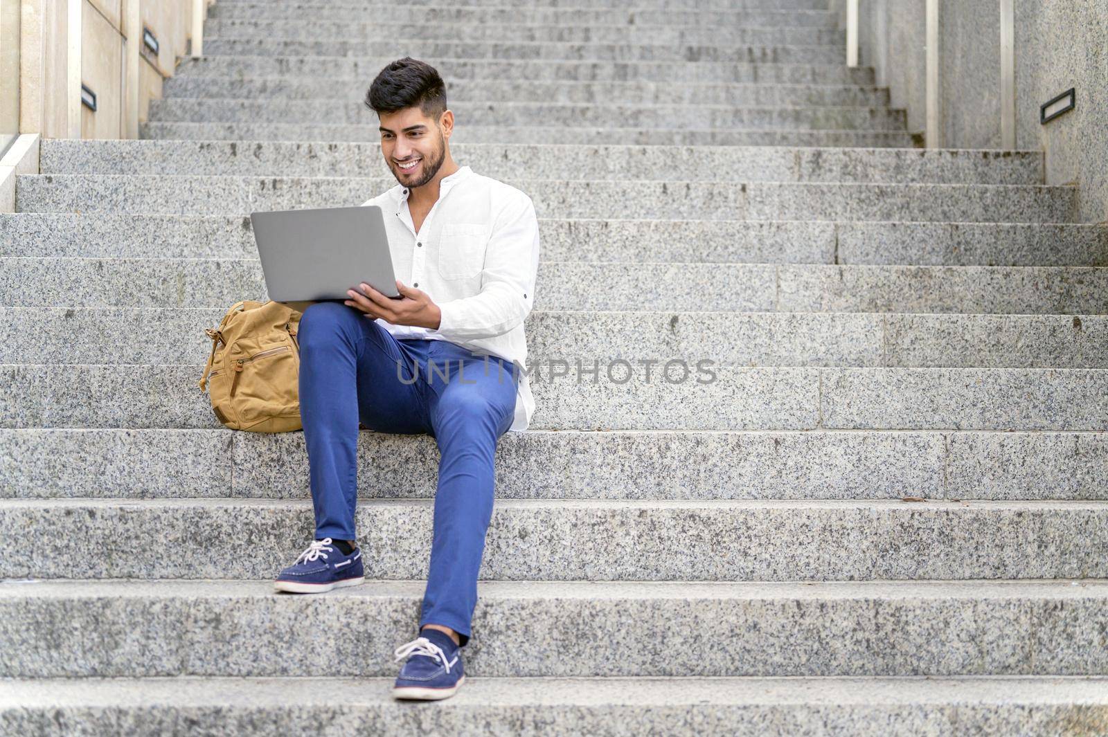 handsome young man working with laptop on stairs. High quality photo
