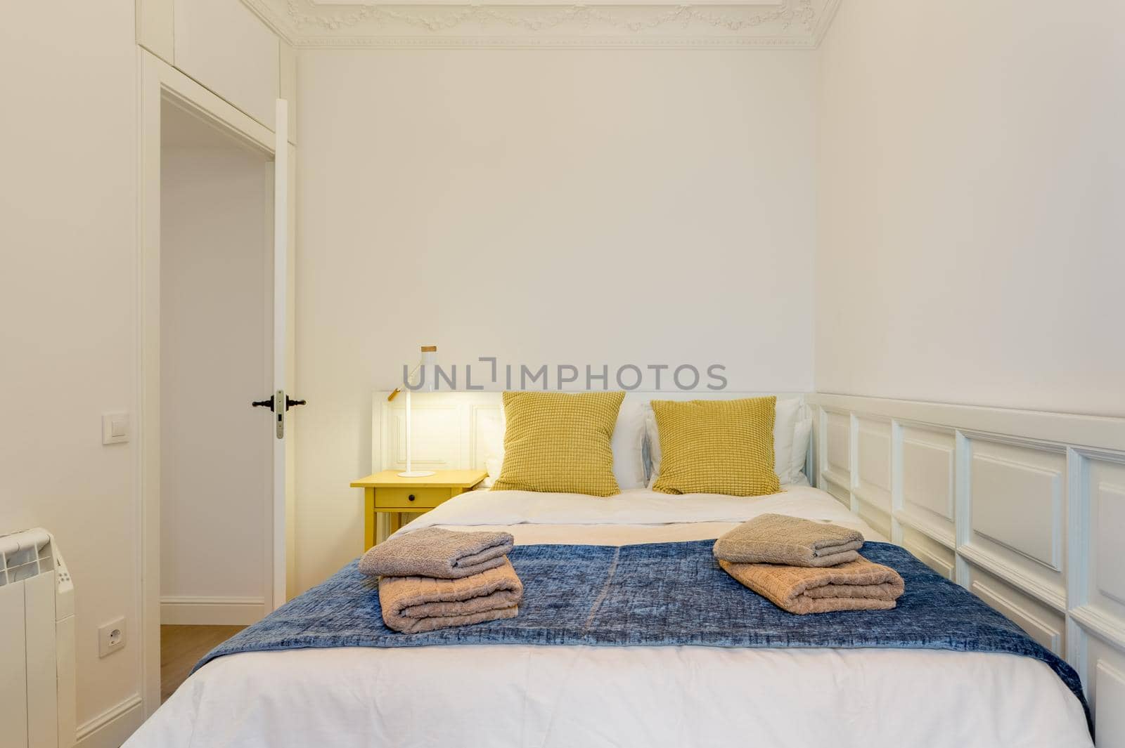 Interior of touristic bedroom. Yellow pillows on bed with towels. An apartment ready for booking by tourists by apavlin