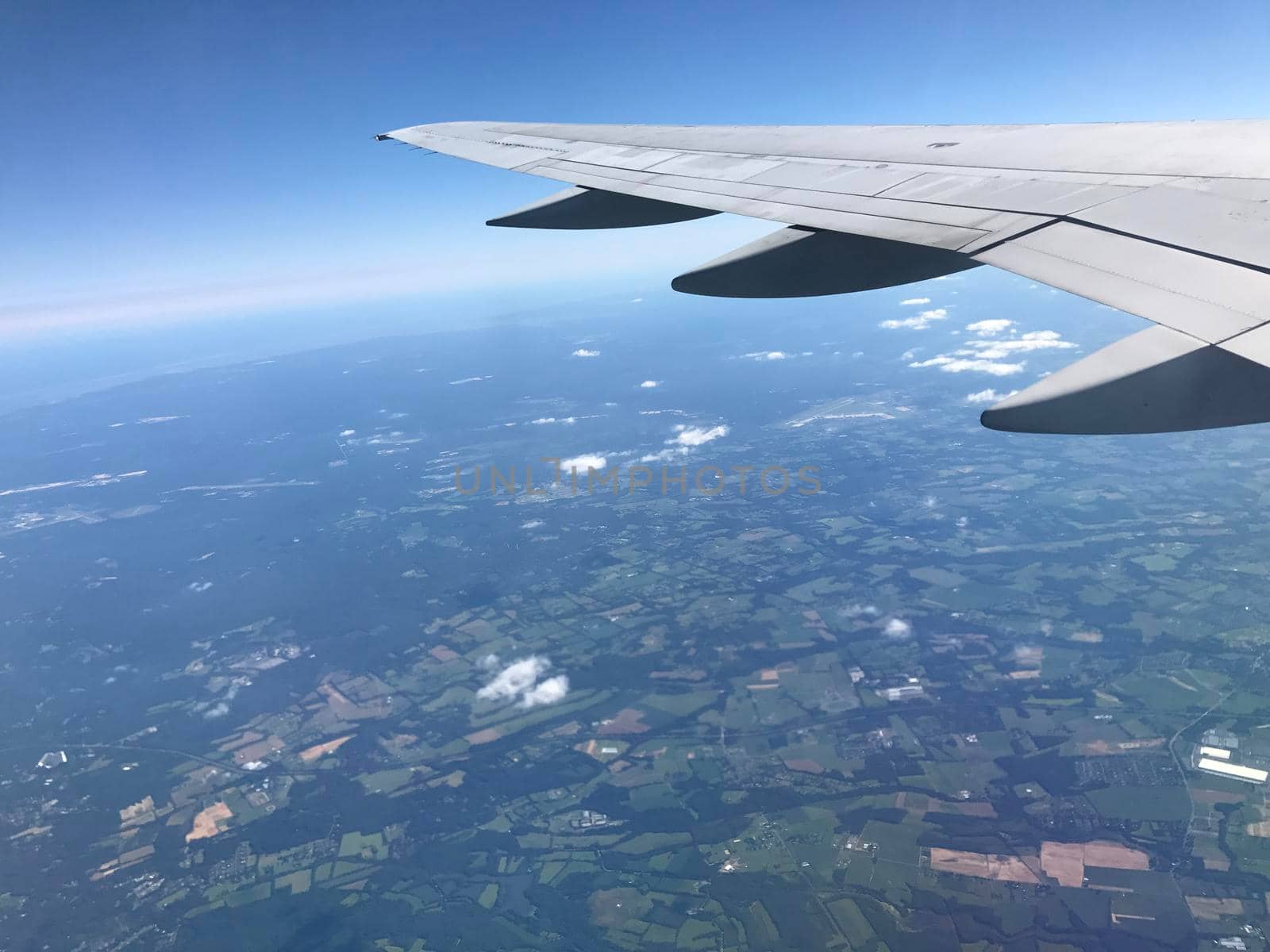 View from airplane wing over blue and green landscape by jyurinko