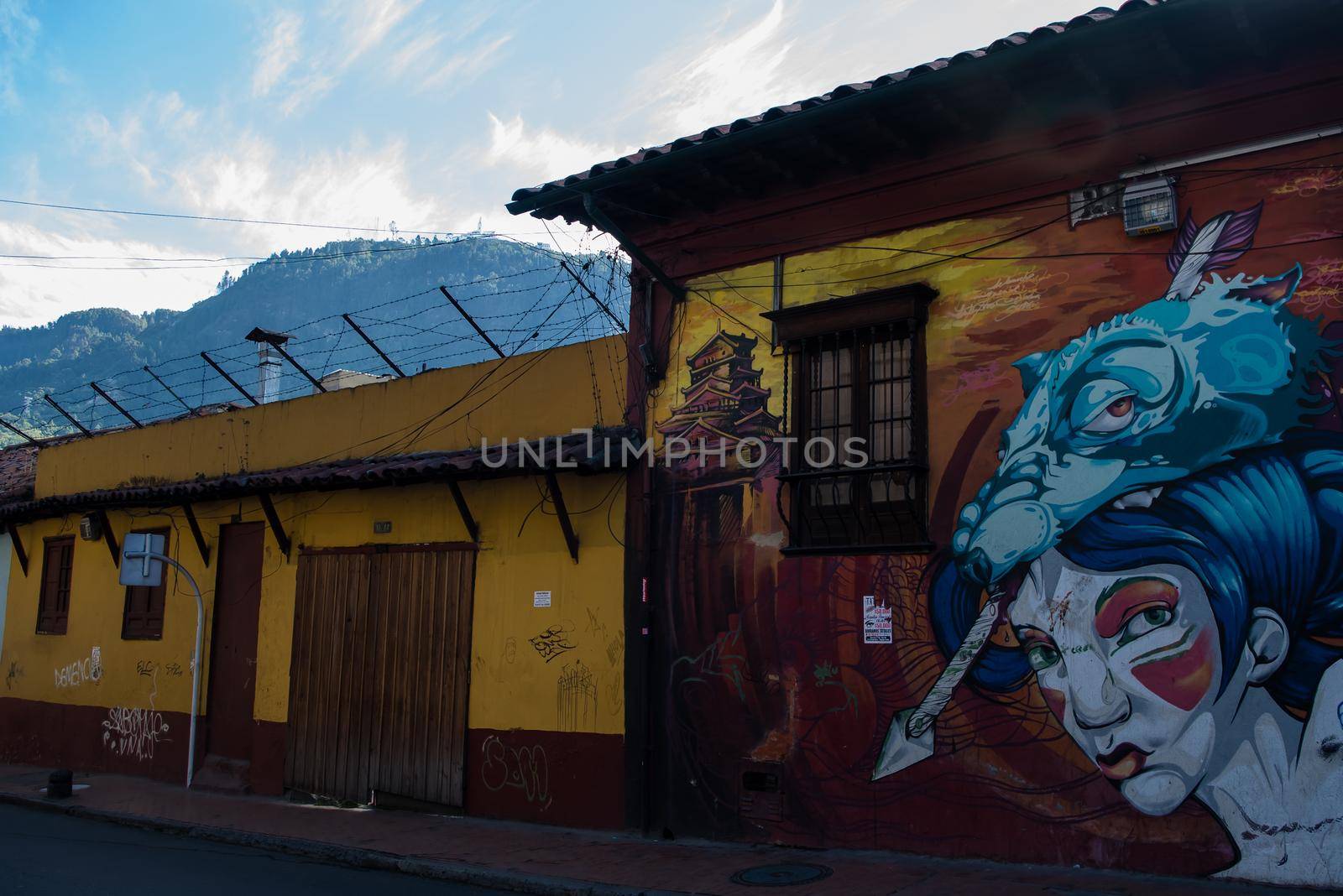 Graffiti buildings with colorful art in Bogota, Colombia with Mount Monserrate in background. by jyurinko