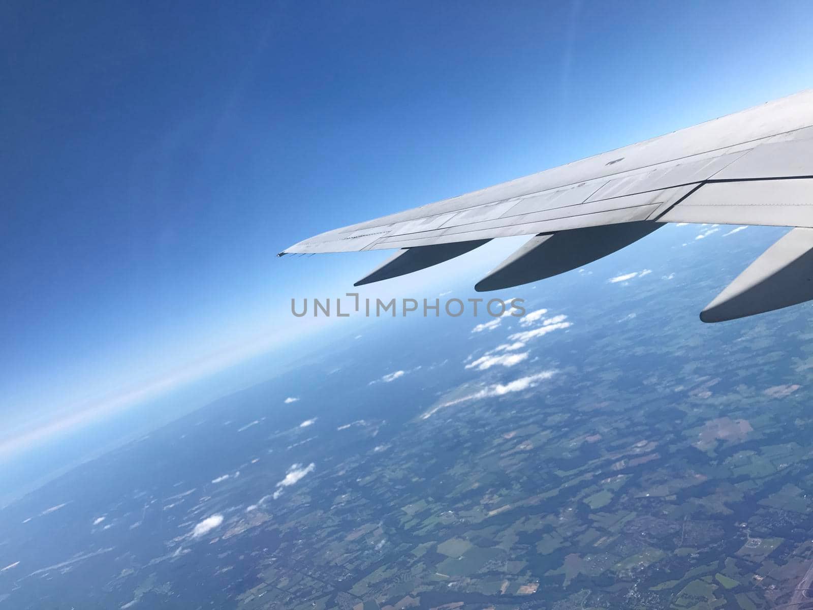 View from window of airplane wing over blue and green landscape