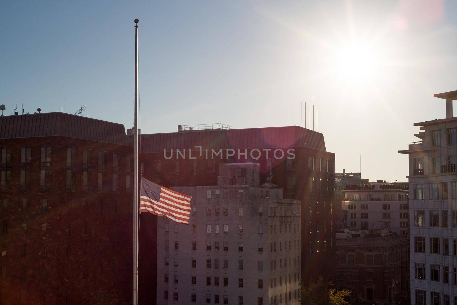 US flag flying at half mast during sunset in Washington DC by jyurinko