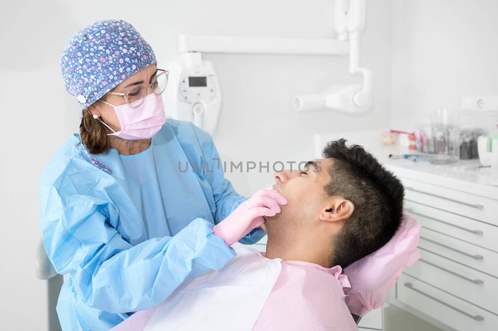 Doctor treats patient teeth in modern dental clinic by HERRAEZ