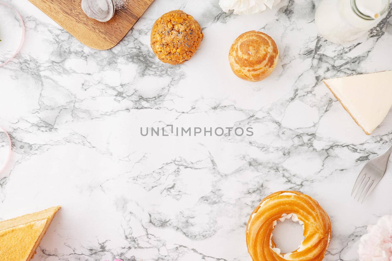 Homemade profitroles pastry filled with custard. Eclairs with cream, French dessert and flowers on marble table top view