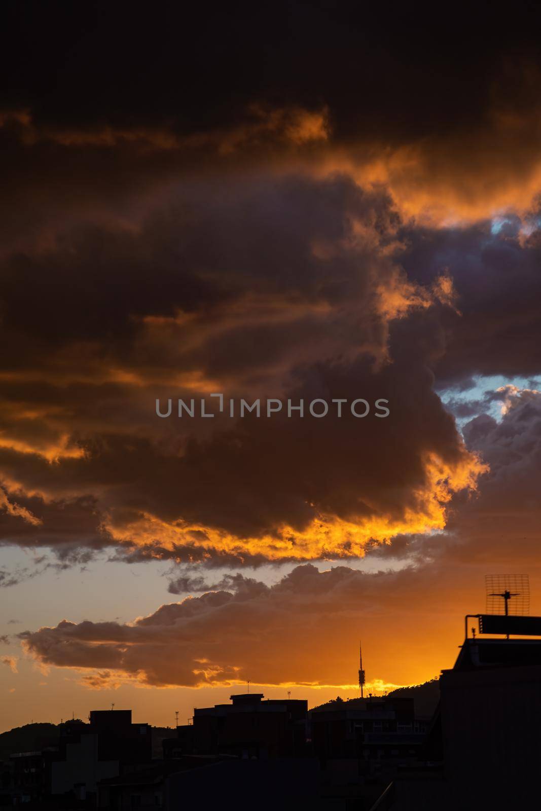 Dramatic stormy sunset sky with orange heavy clouds over city skyline. by apavlin