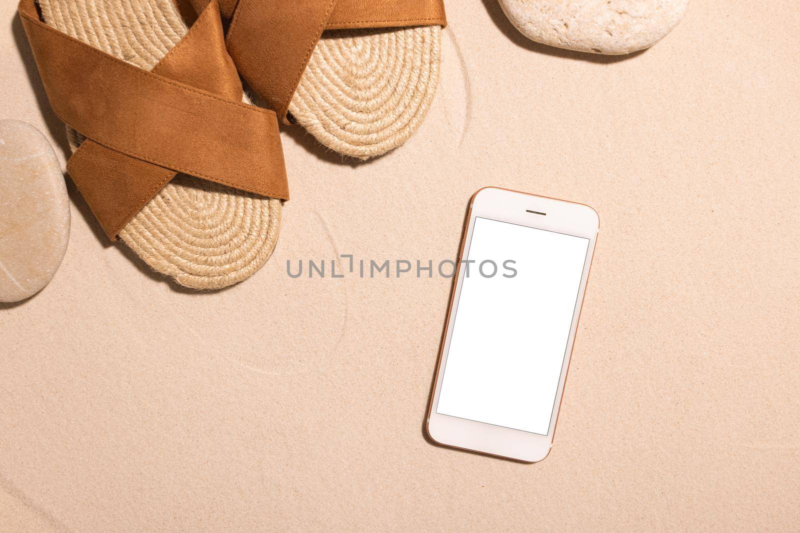 Beach background with mobile phone ,brown sandals and stone on a sandy beach in the sun. Concept: Summer vacation in a warm country. relax by the sea summer time travel top view