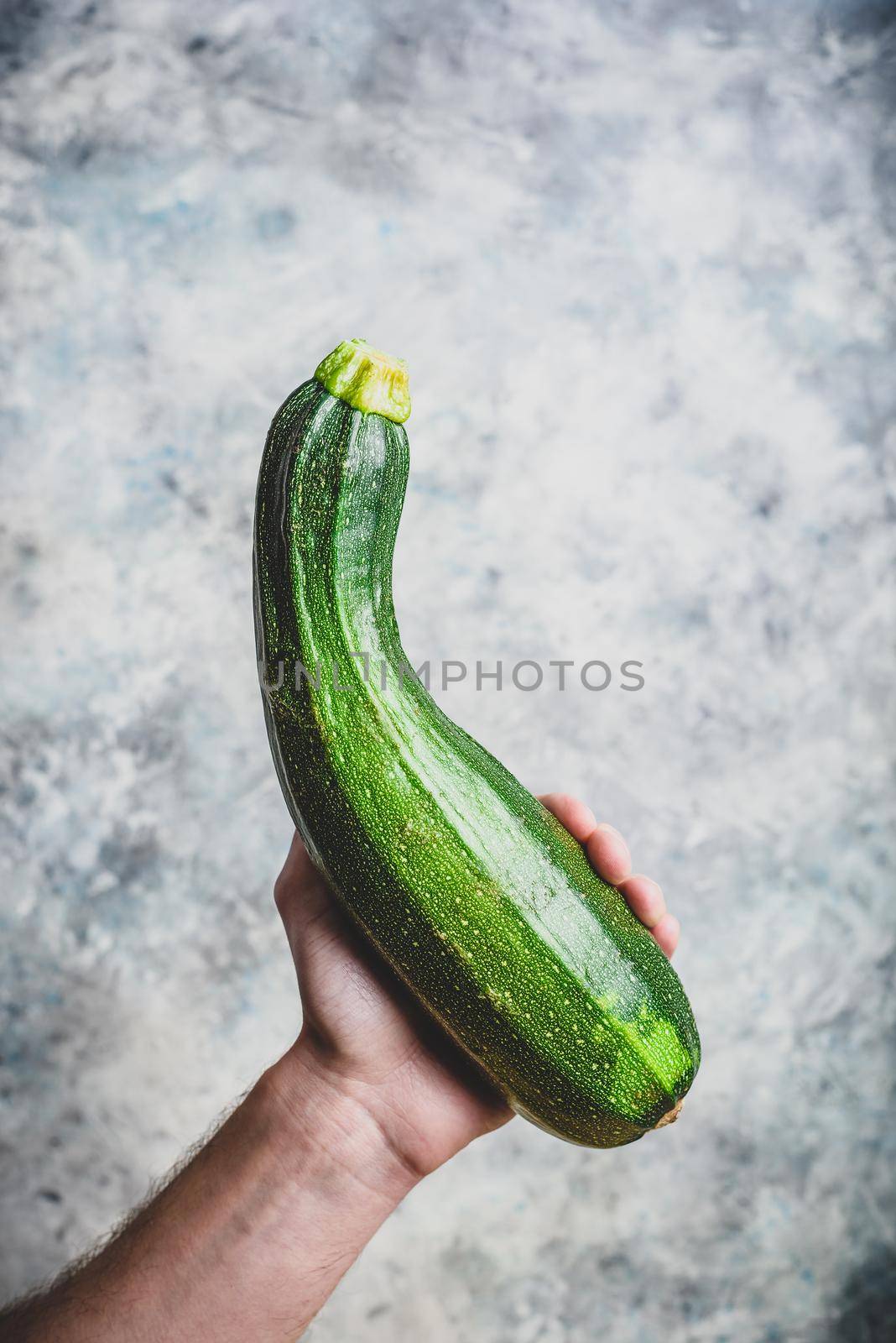 Male hand holding fresh organic zucchini