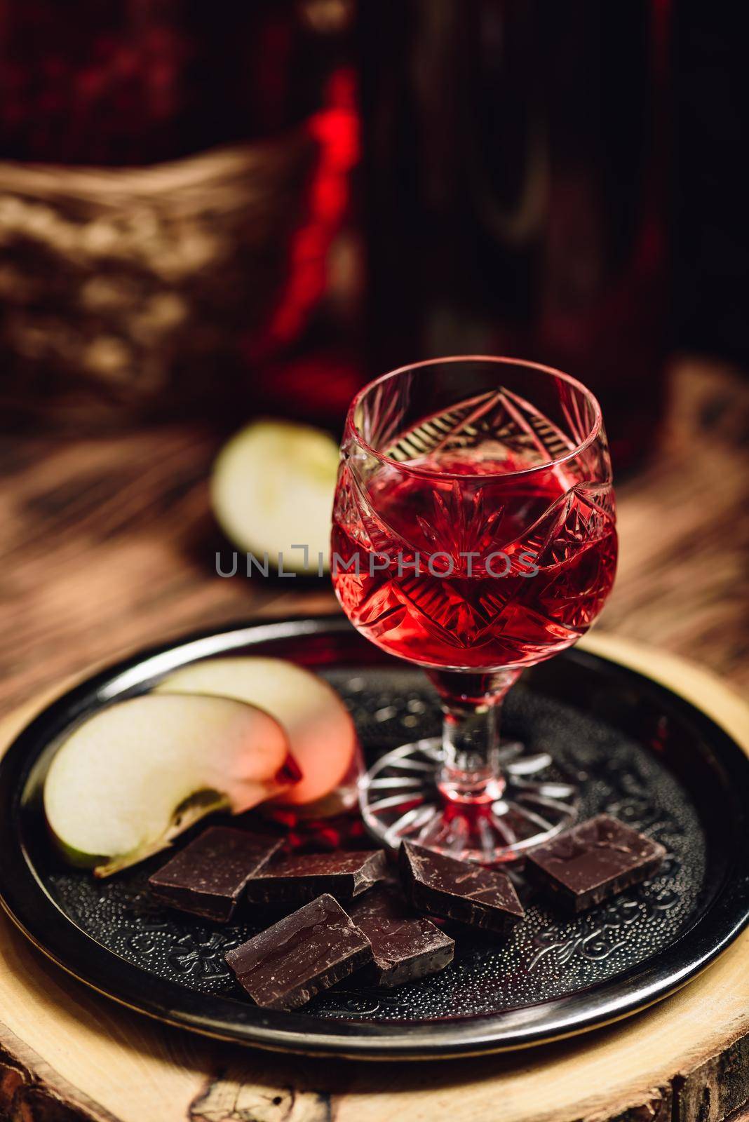 Homemade red currant nalivka and chocolate with sliced apple on metal tray