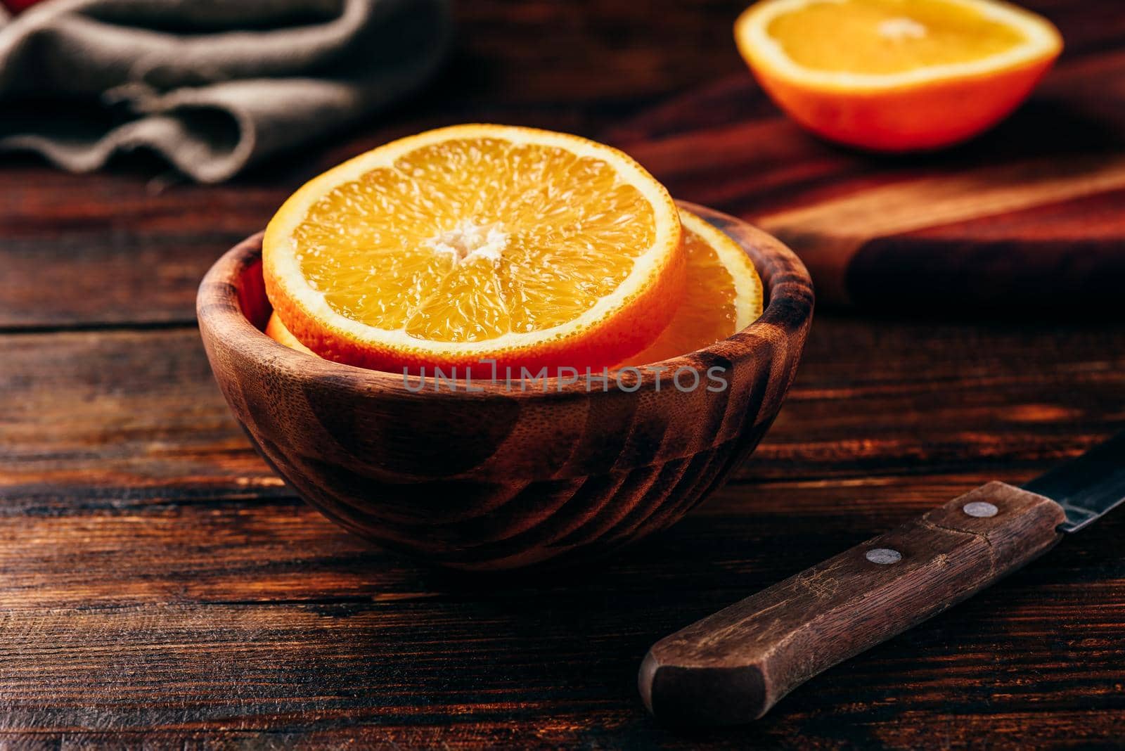 Sliced orange in a wooden bowl in rustic setting