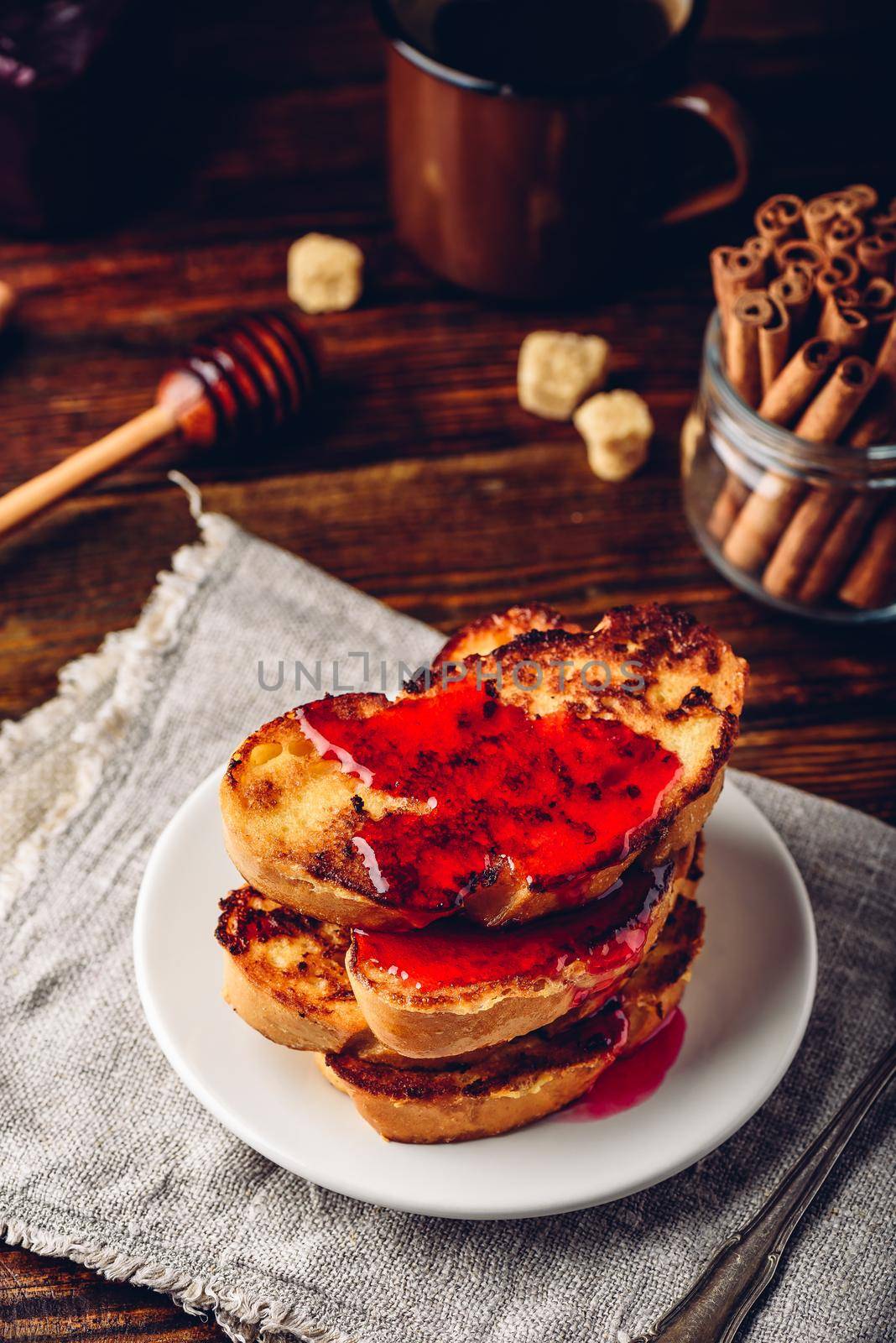 Stack of french toasts with berry syrup on white plate