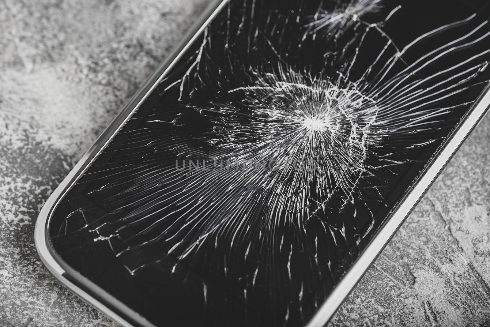 Smartphone with cracked screen over concrete background