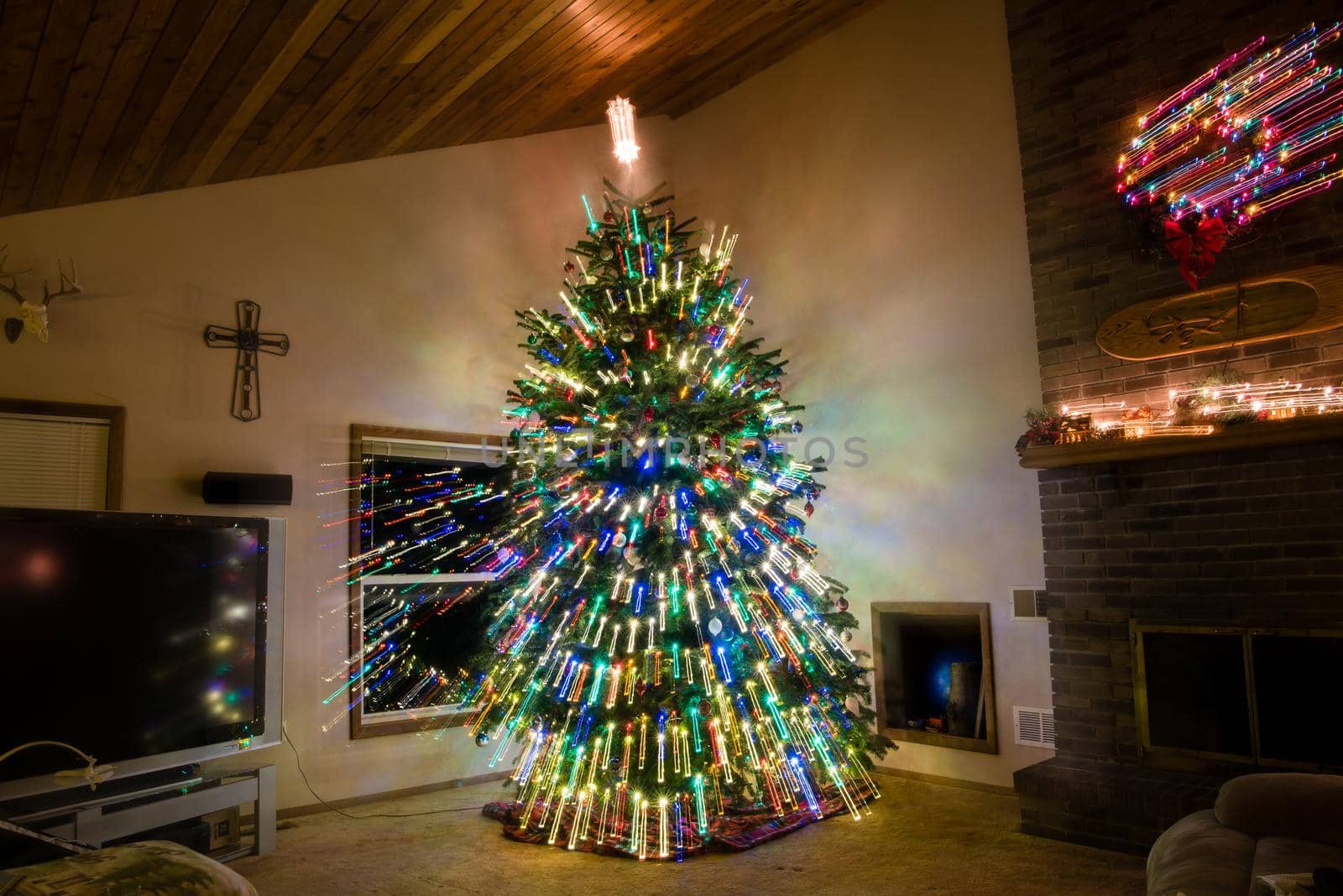 Large decorated Christmas tree inside of living room with light streaks