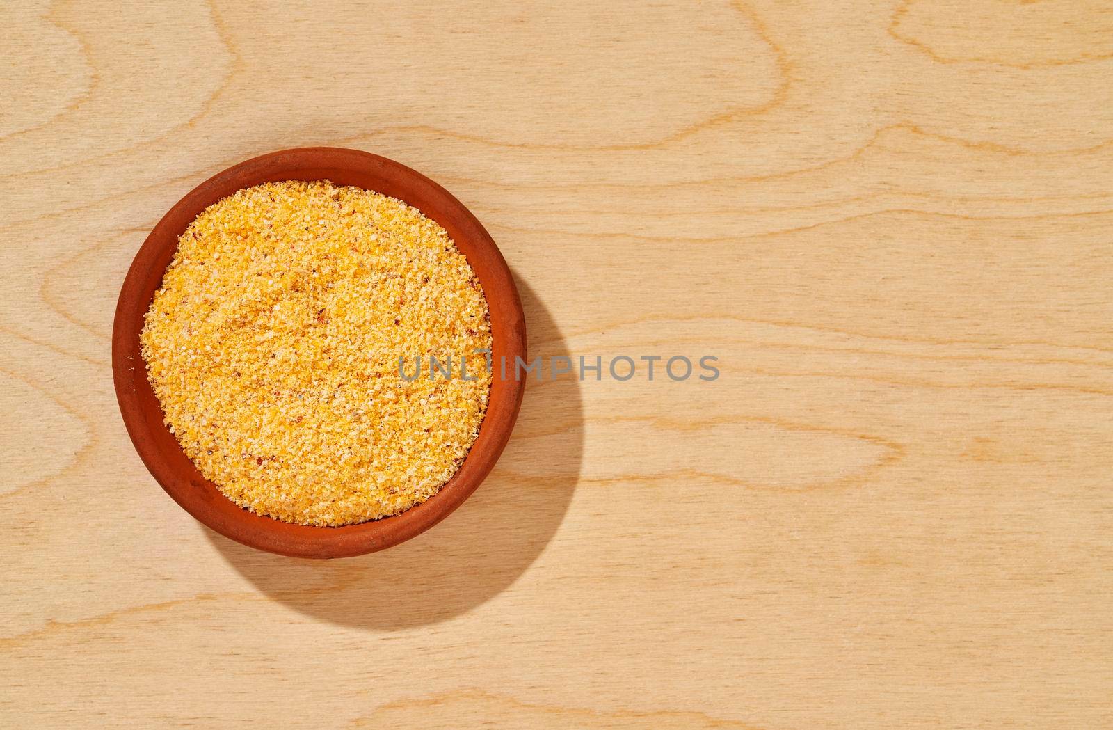 Heap of  polenta in  bowl, yellow grains of cornmeal 