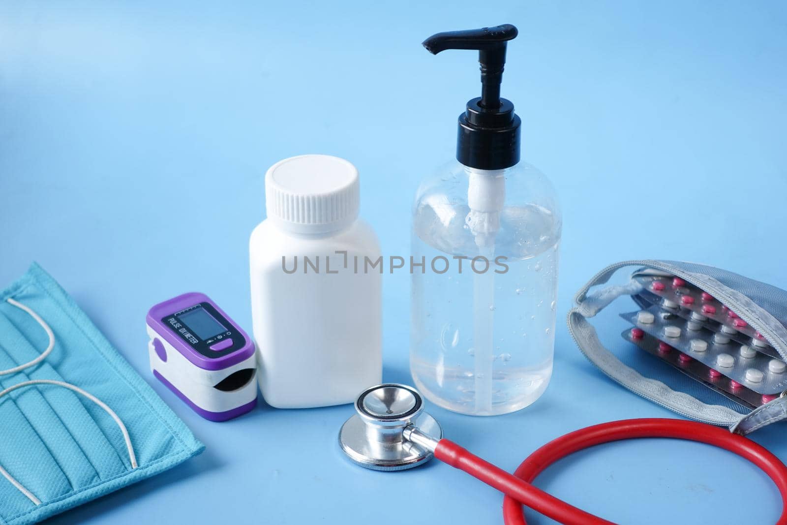 Surgical masks, thermometer and hand sanitizer on blue background .