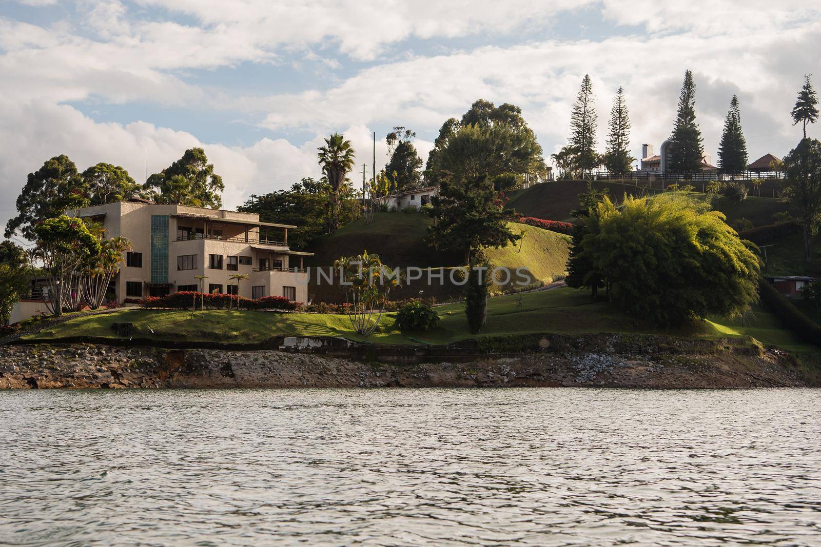 Grassy hillside with cloudy blue sky in the background and water in the foreground. View from a boat